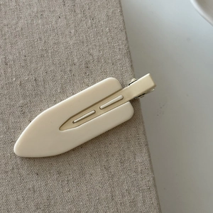 Detailed view of large cream-colored matte hair clip with parallel groove design