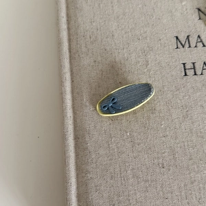 Close-up of denim fabric oval hair clip with yellow piping and blue ribbon detail