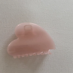 Detail of a sweet pink heart-shaped resin hair claw clip with smooth jelly-like texture