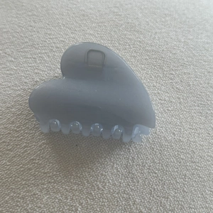Top view of light blue-grey matte claw clip with heart-shaped design and metal spring
