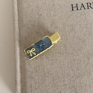 Detailed close-up of a yellow wavy edge hair clip with denim fabric and bow knots