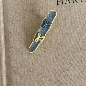 Detail of wavy denim blue hair clip with yellow bow accents on beige fabric background