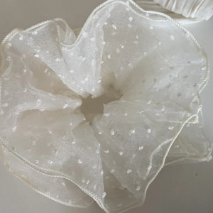 Détail d'un chouchou en maille crème avec texture duveteuse et pois blancs en 3D
