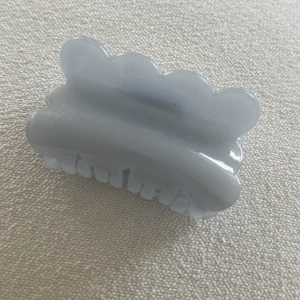 Macro view of light blue wavy shark hair clip with translucent jelly finish on knit fabric