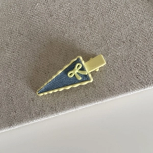 Detail of yellow triangle hair clip with denim texture and small ribbon bow