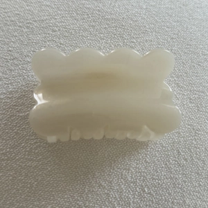 Detail view of the smooth cream jelly hair claw clip with elegant wavy edge design