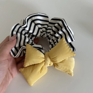 Detailed macro view of black and white striped scrunchie with a bright yellow satin bow