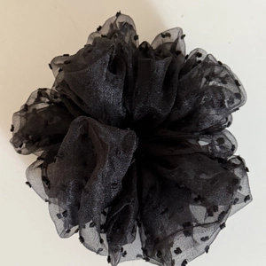 Détail d'un grand chouchou en maille noire avec pois floqués et texture volumineuse
