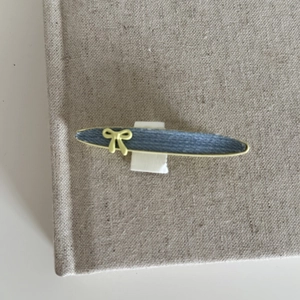 Retro denim blue hair clip with yellow bow accent and metal trim on display card