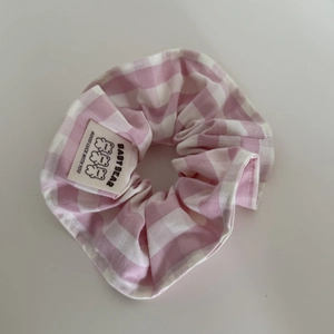 Dettaglio scrunchie a quadretti rosa con etichetta orso e testo Good Luck With You