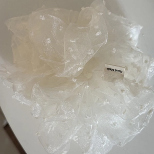 Détail d'un chouchou en organza blanc à pois avec étiquette en tissu Hand Made