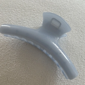 Detail view of large blue jelly hair claw clip with metallic spring on fabric background