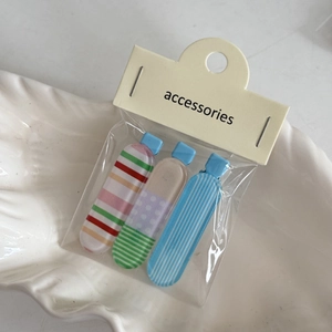 Dettaglio di un set di 3 fermagli per capelli a fiori e strisce su un vassoio decorato
