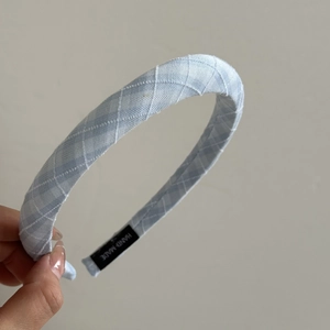 Detail of light blue checkered headband featuring a hand made woven label and knit texture