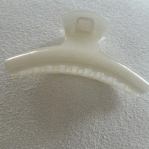 Close-up of a pearlescent cream white hair claw clip with smooth crescent design