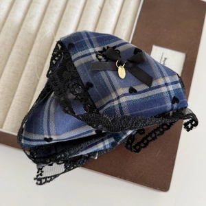 Close-up of navy plaid fabric hair claw with black lace trim and golden oval pendant