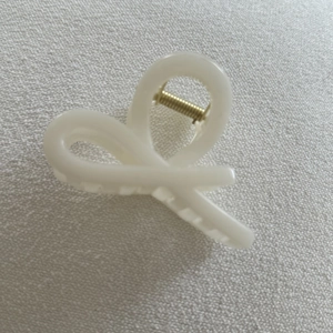 Detail view of the cream white matte hair claw clip featuring a golden metal spring