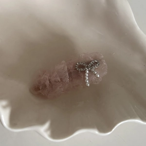 Barrette à cheveux en dentelle rose avec perles et strass sur un plateau coquillage