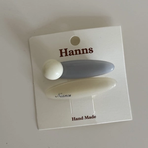 Set of two pastel blue and grey oval hair clips on a white display card for girls