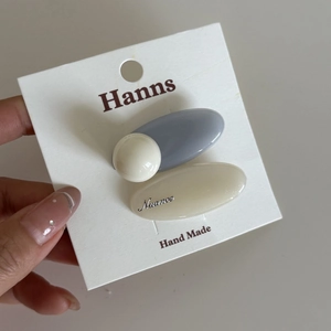 Detail view of pastel blue and cream resin hair clip set on a white card display
