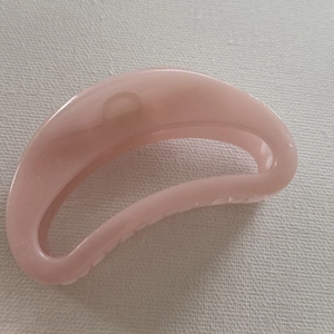 Detailed top view of a light pink translucent resin hair claw clip in half-moon shape