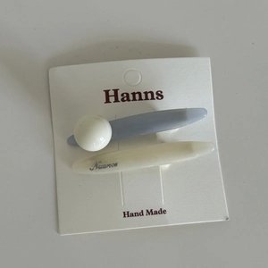 Detail view of two minimalist blue and cream hair clips on original white display card