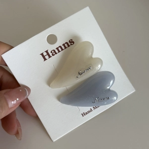 Set of two heart-shaped resin hair clips in off-white and blue with fine gold glitter