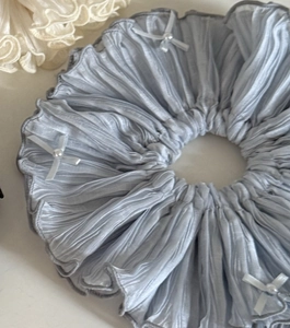 Gros plan du chouchou plissé bleu avec nœuds de perles blanches et satin doux