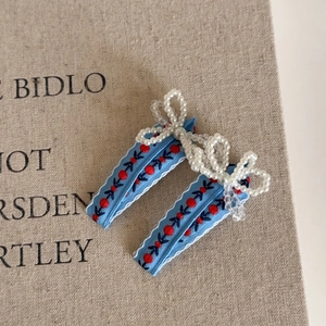 Détail des barrettes avec broderie florale bleue et nœuds en perles artisanales