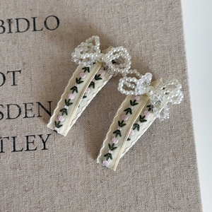 Détail de barrettes à fleurs brodées avec nœud en perles et ruban de style vintage