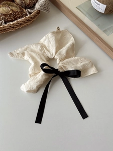 Detailed embroidery texture of large white scrunchie with long black satin bow ribbon