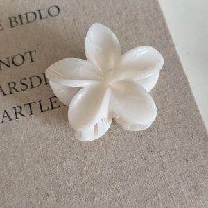 Détail macro d'une pince à cheveux fleur de frangipanier en acétate crème de qualité