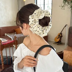 Elegant oversized satin scrunchie with classic black polka dots and ruffle edge detail