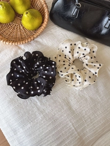 Polka dot satin scrunchies in black and cream colors styled in a lifestyle home setting