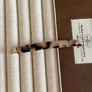 Detailed close-up of a tortoiseshell acetate hair clip with gold handmade engraving