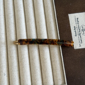 Close-up of tortoise shell acetate hair clip with golden handmade logo on display tray