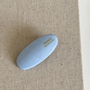 Nahaufnahme einer hellblauen ovalen Haarklammer mit goldenem France Handmade Schriftzug