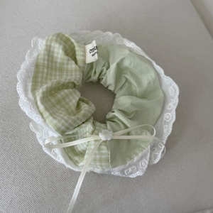 Detailed close-up of large green plaid scrunchie with lace trim and ribbon bow