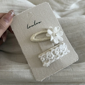 Detailed macro view of two-piece cream lace hair clips with floral and pearl accents