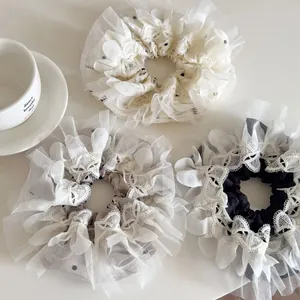 Detail view of double-layer embroidered dot lace scrunchies in three soft colors