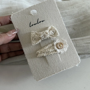 Close-up of beige lace bow and woven flower hair clips with vintage golden buttons