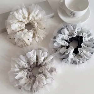 Three oversized polka dot organza hair scrunchies with elegant lace trim in neutral tones