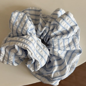 Detail view of blue and white plaid scrunchie with seersucker texture and ruffled design