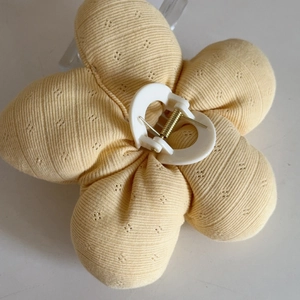 Close-up of yellow knitted flower hair claw clip with diamond pattern and heart core
