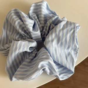 Detail of oversized blue and white striped fabric scrunchie with soft cotton texture