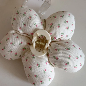 Detailed view of floral knit fabric hair claw clip with cream resin center and gold spring