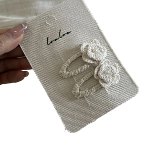 Pair of handmade crochet flower hair clips with pearls on a display card