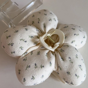Close-up of a floral fabric claw clip featuring a 3D padded flower design in purple and cream