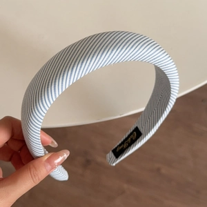 Close-up of blue and white striped sponge headband with premium fabric texture and inner tag