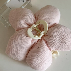 Macro detail of a pink fabric flower hair claw clip with a textured diamond pattern